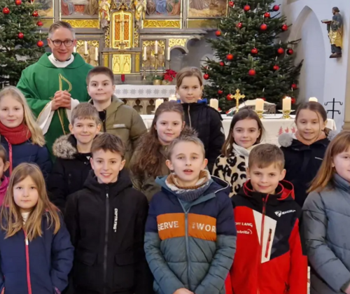 Die Grundschulkinder und Pfarrer Adam Karolczak neben einer Jesus-Statue mit der Aufschrift „Ihr seid meine Freunde”. (Bild: Felix Hartung)